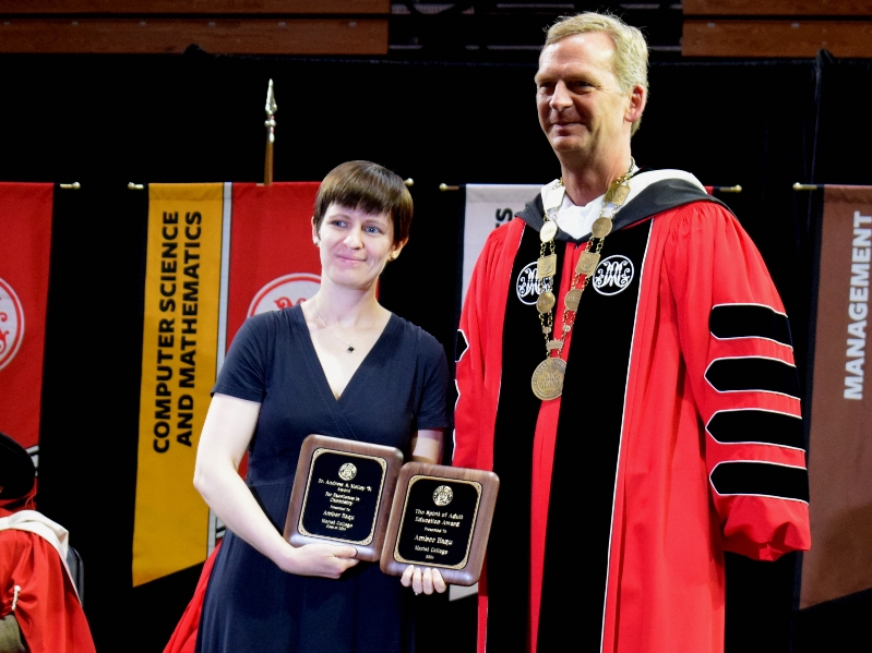 Amber in a black dress, receiving two plaques