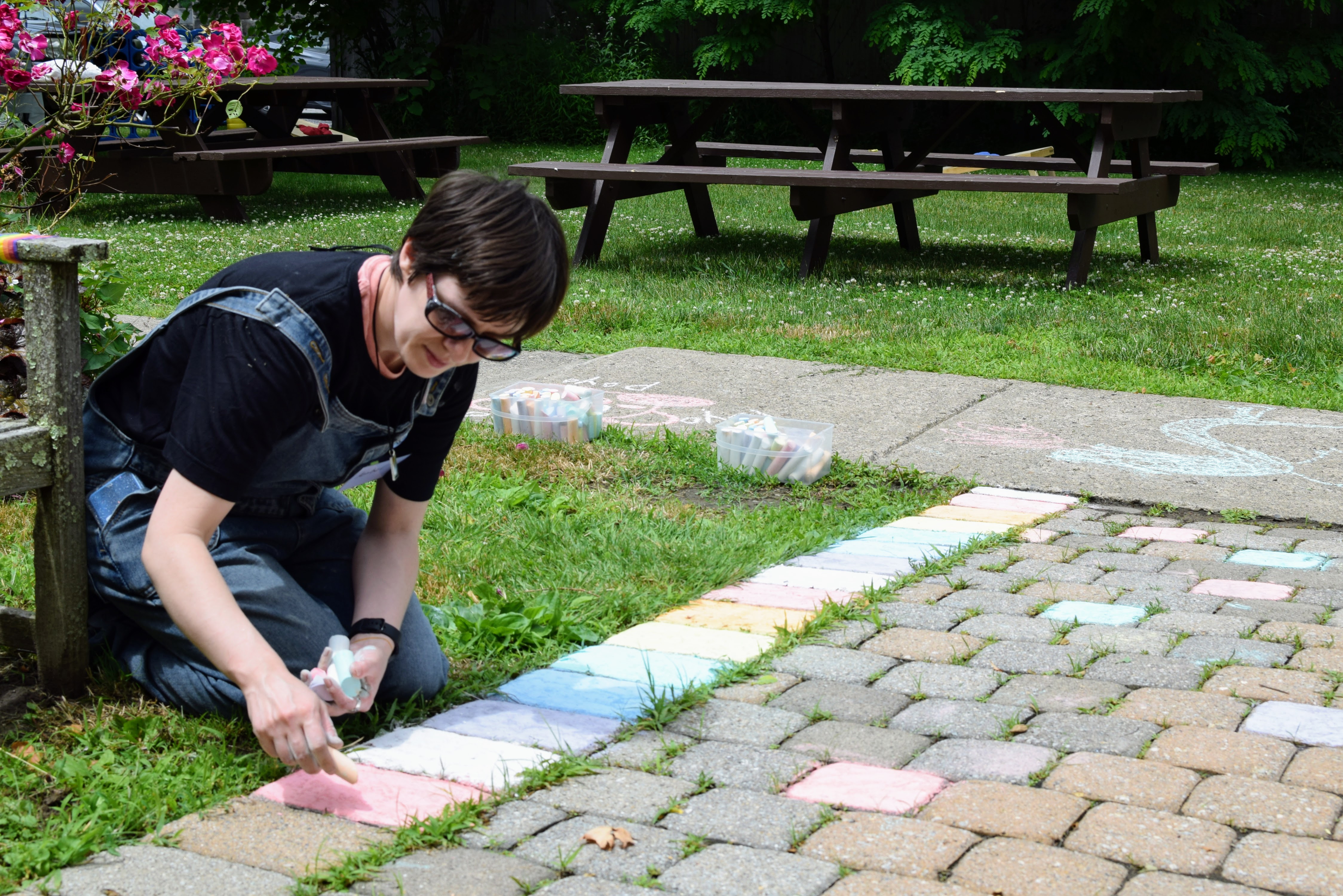 A short-haired brunette person drawing Pride flags in chalk