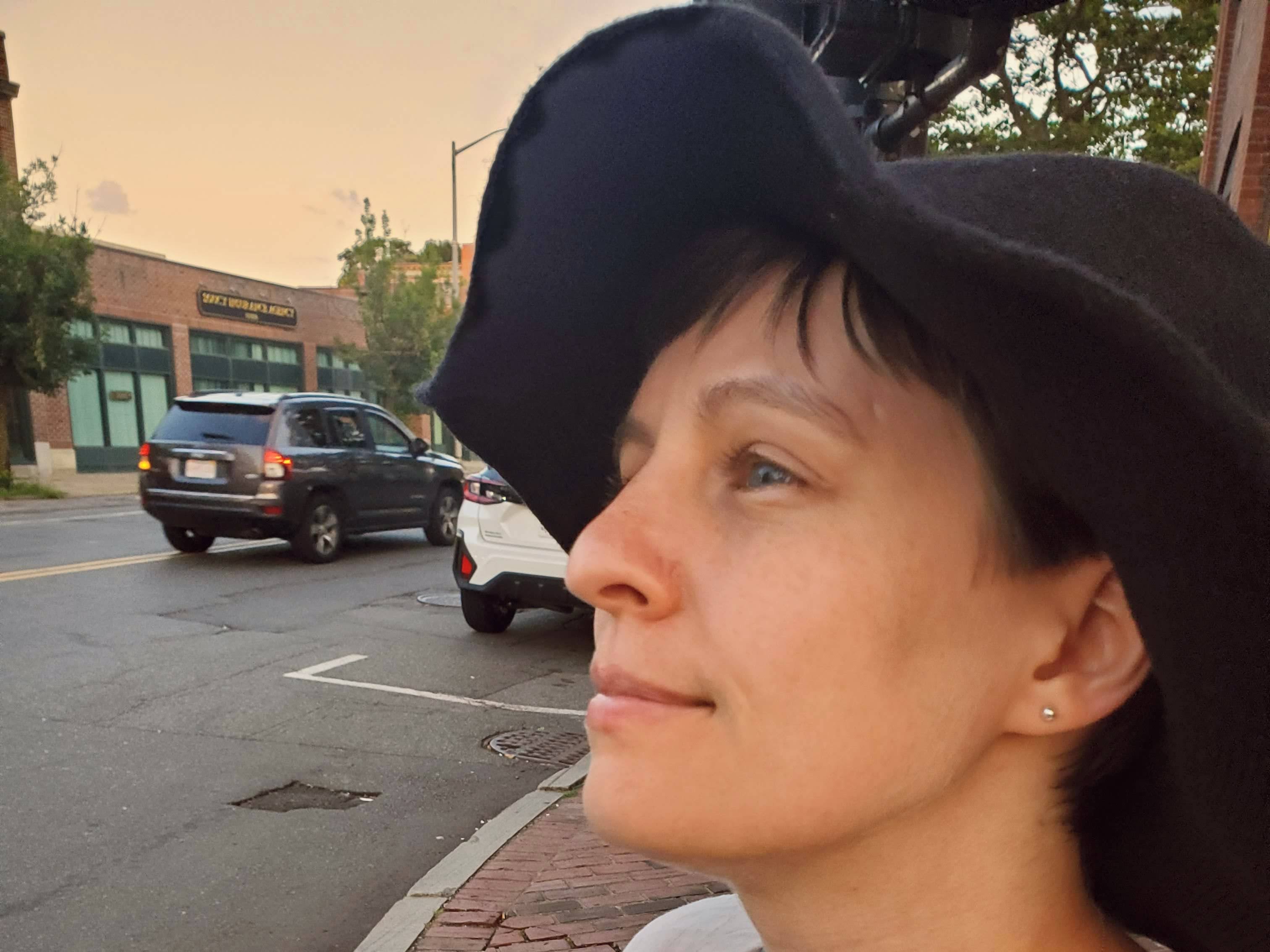 Closeup of Amber looking into the middle distance, wearing a black witch hat