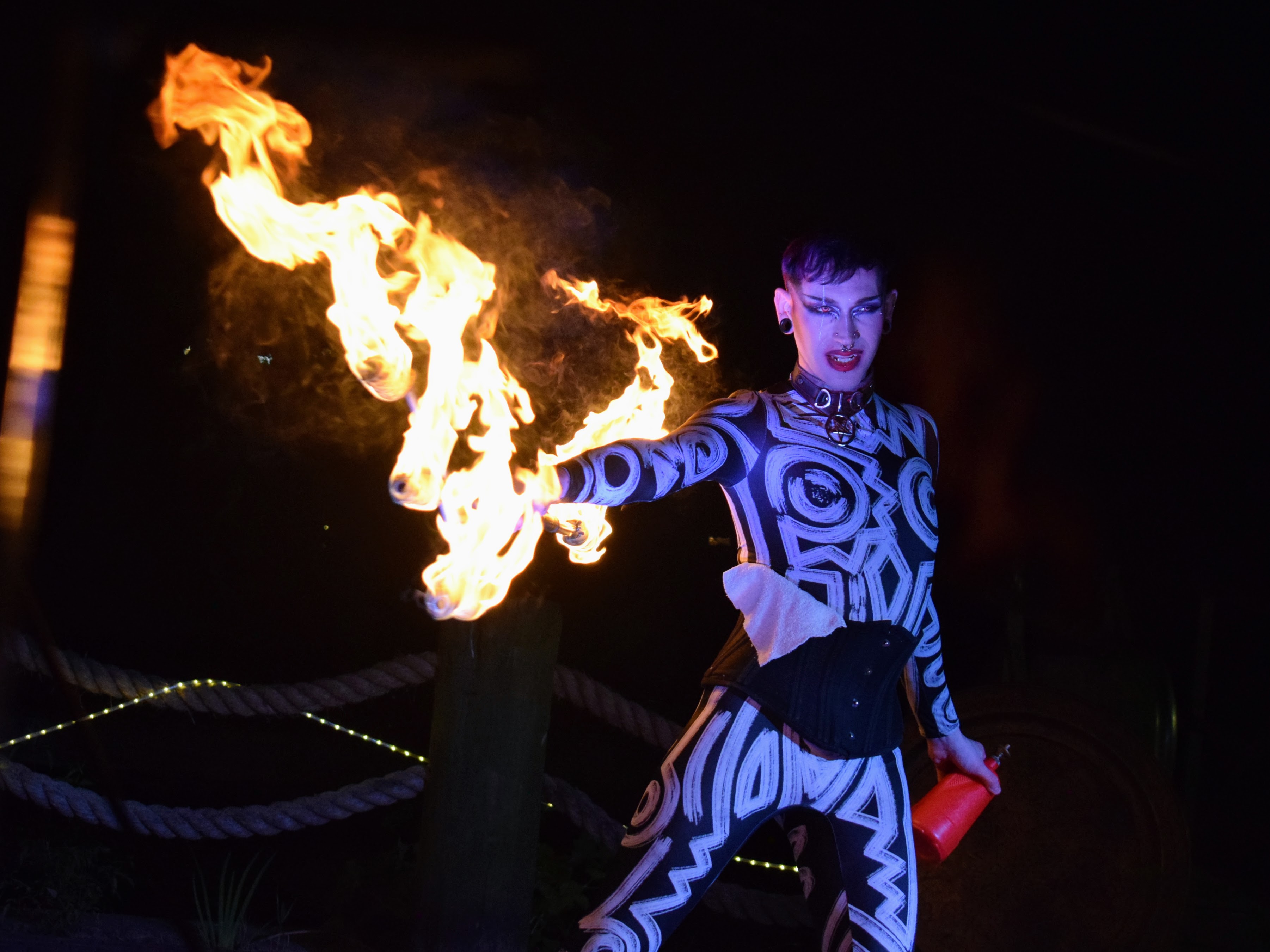 A man with dyed red hair and fangs, holding a flaming trident