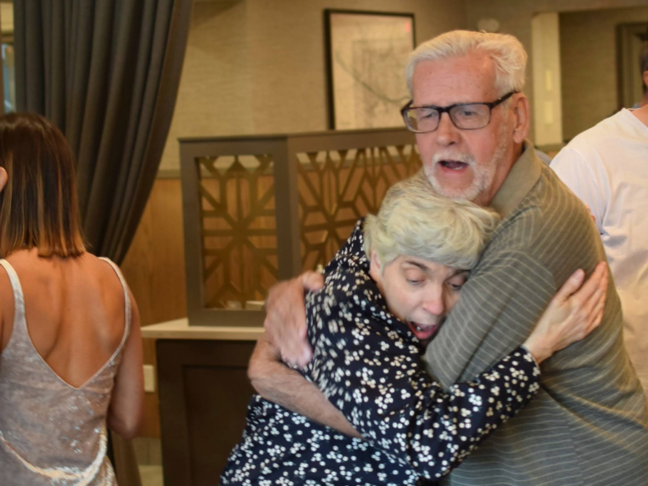 A white haired man holding a woman