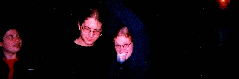 A Man looking down, a woman with a cup in her mouth making a silly pose.